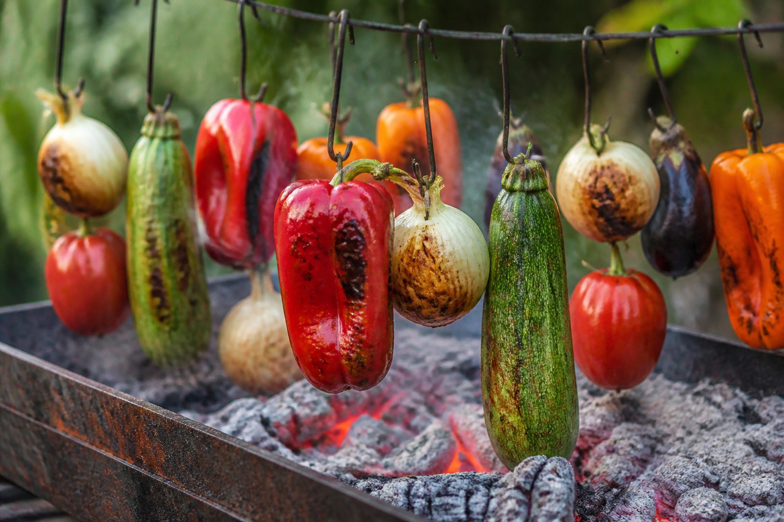 Varal de pimentões, cebolas, abobrinhas, tomates e berinjelas assando sobre a brasa